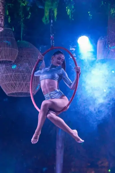 Lyra aerial hoop performer in a metallic outfit suspended inside a lit hoop with wicker lanterns in the background at Nouba, Marrakech