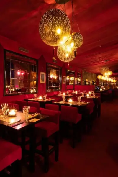 Candlelit tables with red velvet chairs and golden lamps at Palais Jad Mahal, Marrakech