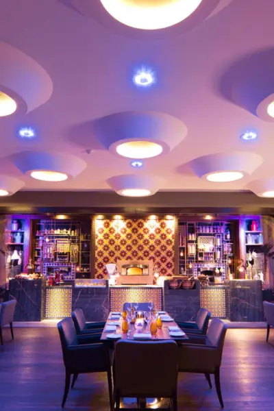 Elegant dining area at Quattro Marrakech with a modern bar backdrop, decorative tile accents, and recessed circular ceiling lights