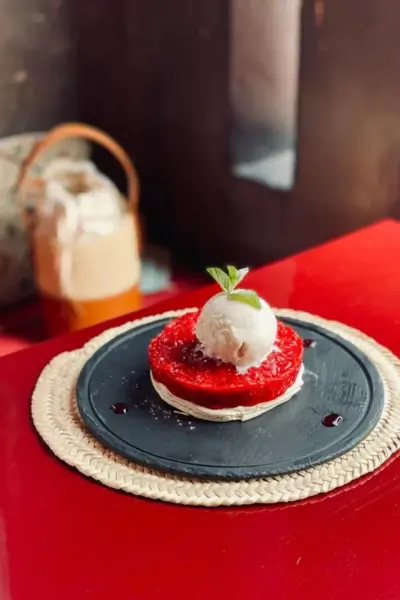 Close-up of a berry tart topped with vanilla ice cream and fresh mint on a black slate plate at Terrasse des Épices, Marrakech